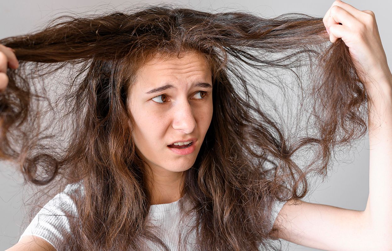 Woman with an upset expression looking at her frizzy hair