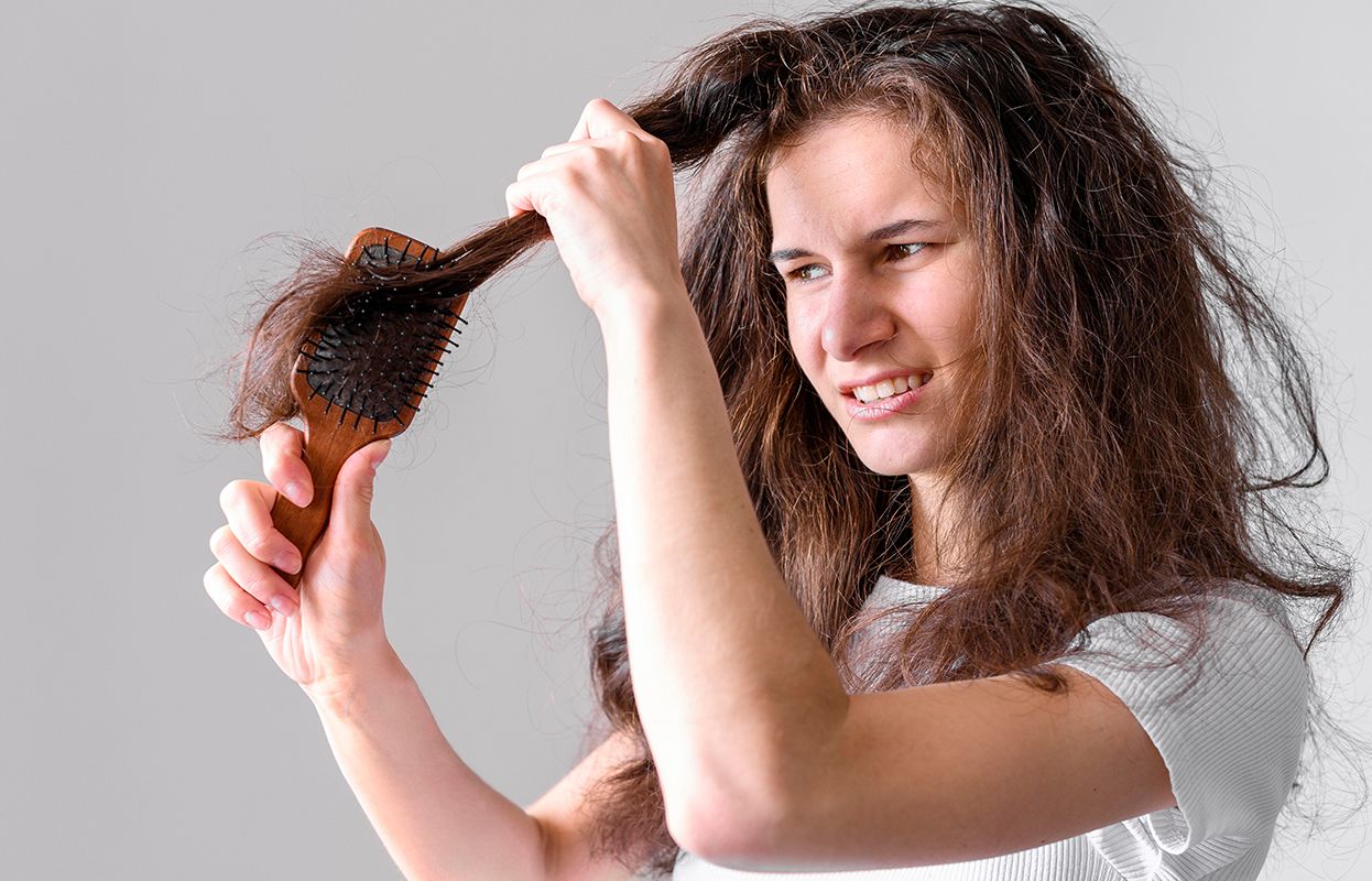 Woman brushing tangled hair with a comb