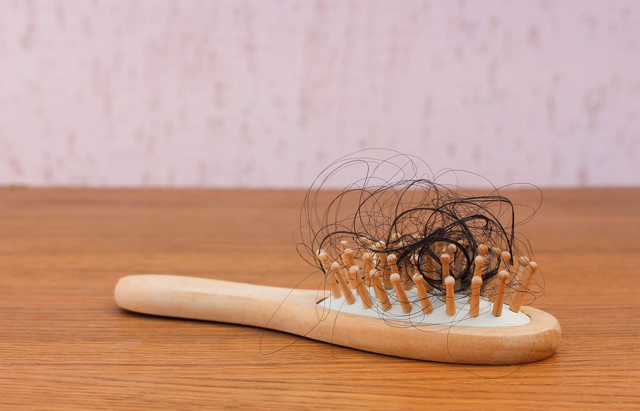 Wooden comb with dry and damaged hair stuck between its teeth