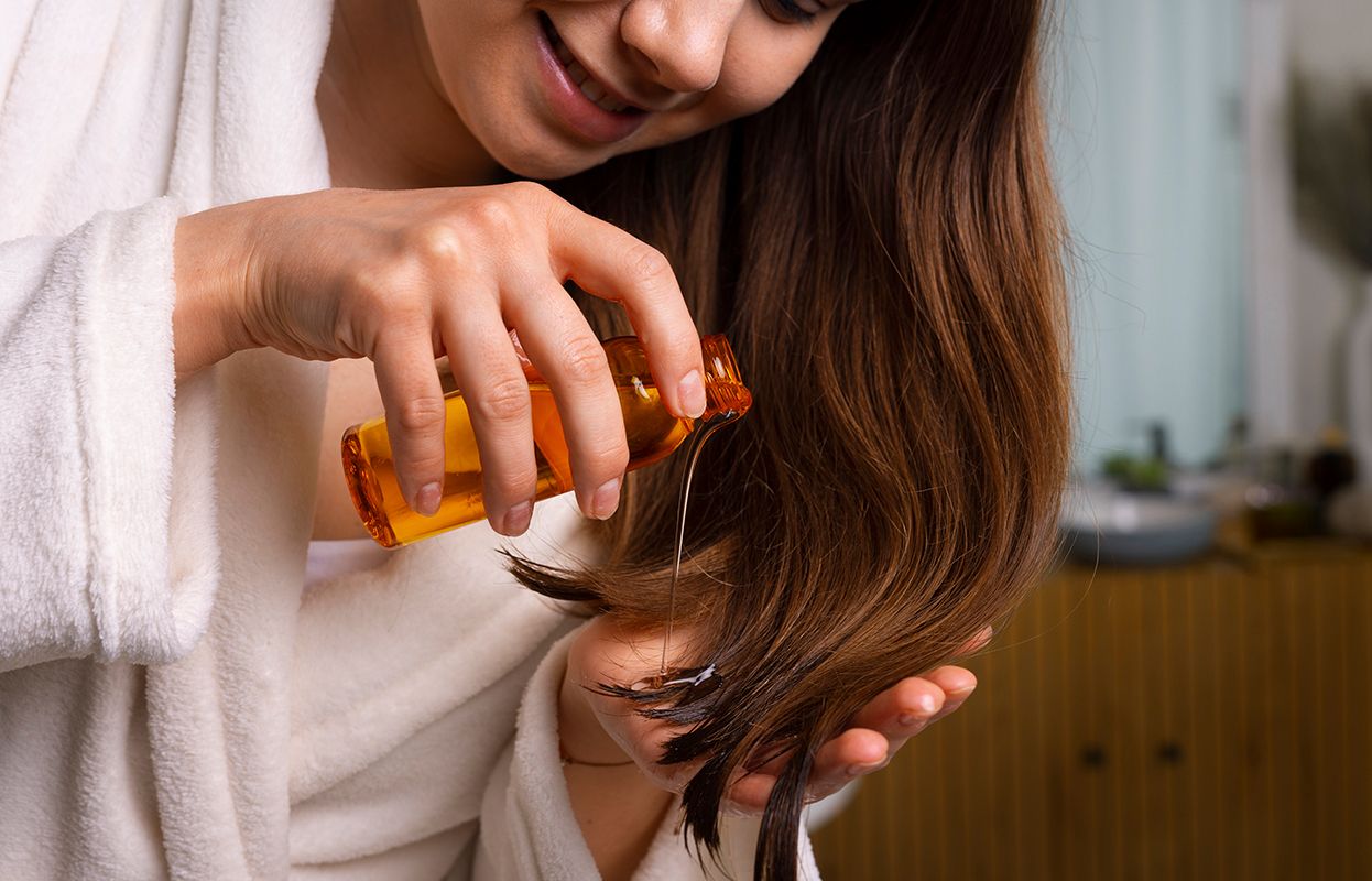 Woman pouring Jasmine Hair Oil in her palm with a calm expression on her face