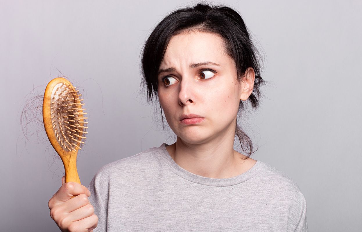 a woman with a comb full of hair, looks depressed